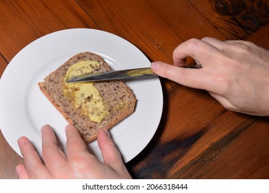 Hands Buttering Wholegrain Toast On A White Plate