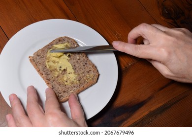 Hands Buttering Wholegrain Toast On A White Plate