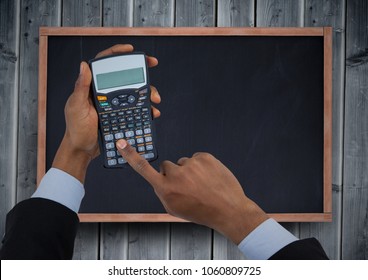 Hands with calculator against chalkboard and grey wood panel