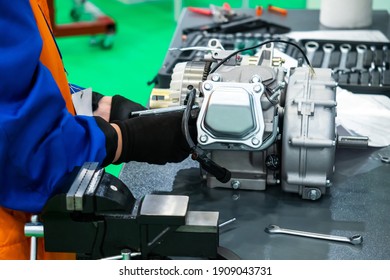 Hands Of A Car Foreman During Work. He's Fixing Some Car Part. Man In A Uniform Works With Auto Parts. Concept Is A Career As Automotive Locksmith. Work In A Car Workshop. Manufacturing Of Auto Parts