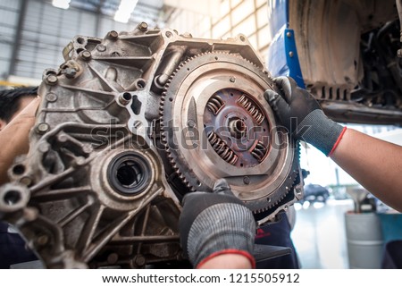 Hands of car mechanic working in auto repair service. Car mechanic fixing flywheel
