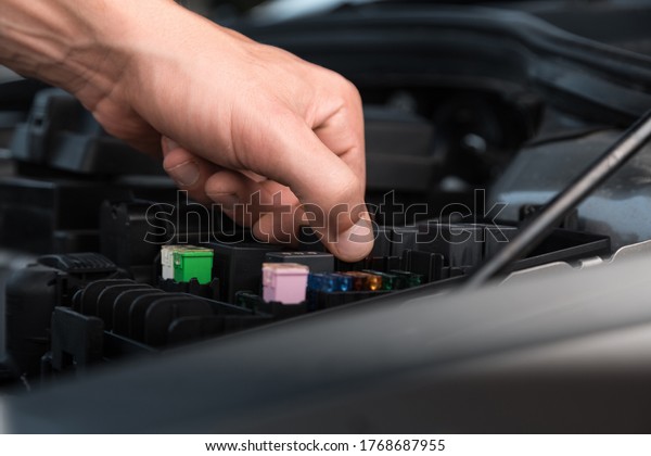 Hands of car mechanic working in auto repair\
service with a car\
battery