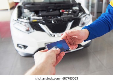 Hands Of Car Mechanic With Wrench In Garage, Payment By Credit Card.