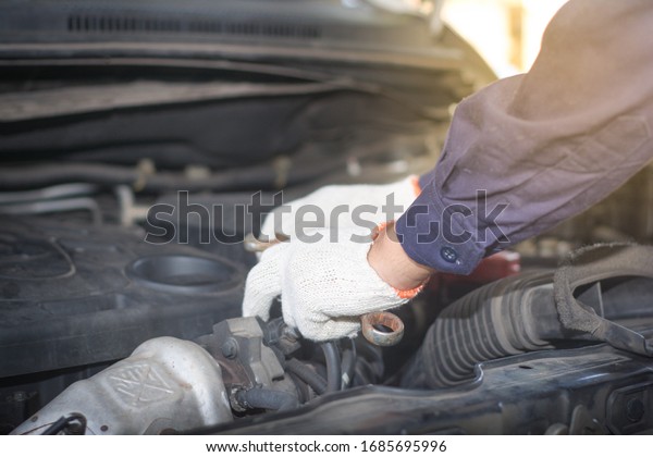 Hands of car\
mechanic/technician is repairing/checking under the front car hood\
at the car service\
station.