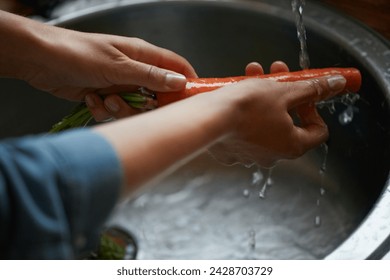 Hands, carrots and washing vegetables or healthy food in sink, preparing meal and kitchen while ready to cook. Person, rinsing fresh produce in basin at home for diet or organic recipe for wellness - Powered by Shutterstock