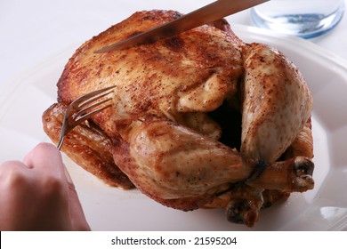 Hands Carving Rotisserie Chicken With Fork And Knife