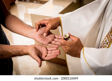 Hands Of A Catholic Priest Applying The Oil For The Anointing Of The Sick. Sacraments Of The Catholic Christian Religion In Church.