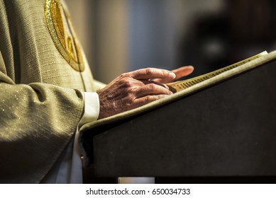 Hands of catholic priest reading a bible.
