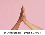 Hands of Caucasian man and black African American giving each other five on pink background. The concept of racism and all lives matter