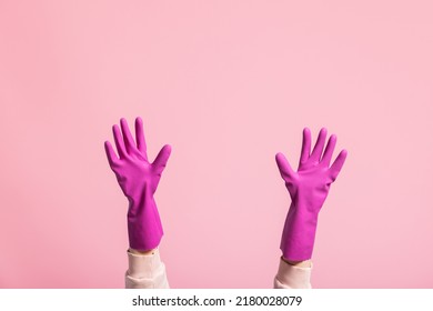 Hands of Caucasian young woman wearing cleaning gloves on isolated pink background, cleaning at home, washing dishes.