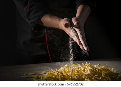 Hands of chef cooking with flour on dark black background.