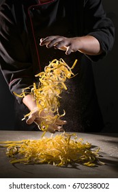 Hands of chef cooking pasta spaghetti powdering by flour on dark black background with space area for text recipe book or menu design. Food banner, big size resolution.