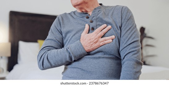 Hands, chest pain and closeup of senior man in bedroom with injury, hurt or accident at nursing home. Sick, ill and zoom of elderly male person in retirement with asthma or heart attack at house. - Powered by Shutterstock