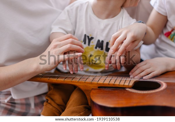 Hands of a child with cerebral palsy\
close-up. Music rehabilitation. Musical instrument guitar strings.\
Vibration sounds. Lessons with the\
disabled