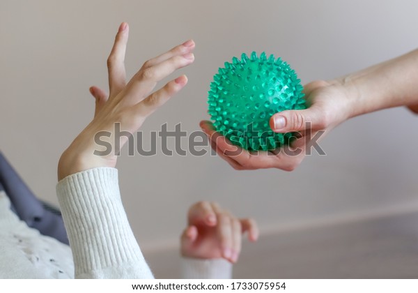 hands of a child with cerebral palsy\
exercises with a ball development of tactile\
sensations