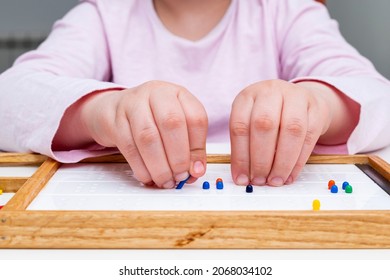 Hands Of A Child Close-up. Picking Up The Mosaic.  Braille Board For Learning Alphabet.