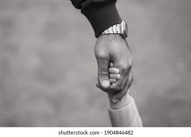 Hands of a child and dad close up. Dad carefully holds the child's hand. Black and white photography of hands. - Powered by Shutterstock