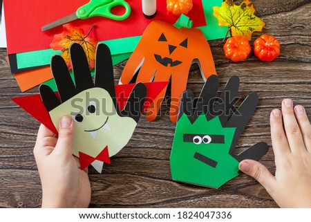 In the hands of a child Greeting card halloween on wooden table. Children's creativity project, crafts, crafts for kids.

