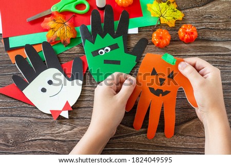 In the hands of a child Greeting card halloween on wooden table. Children's creativity project, crafts, crafts for kids.
