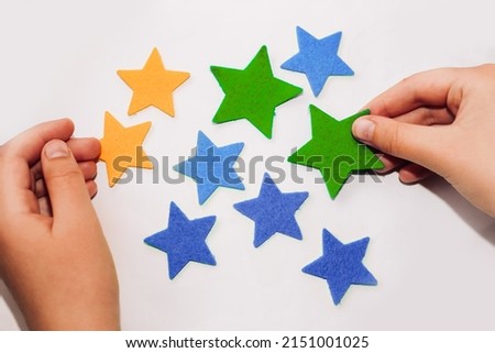 The hands of a child make an applique of felt stickers of stars.