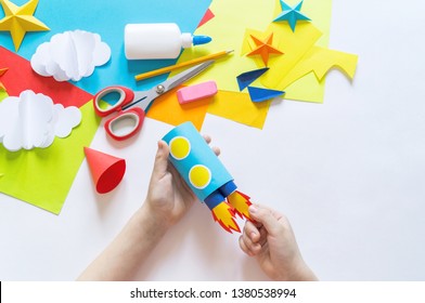 hands of the child make a paper craft rocket. Cosmos clouds and stars colored paper. The creative process. Kindergarten and school development. Master Class. - Powered by Shutterstock