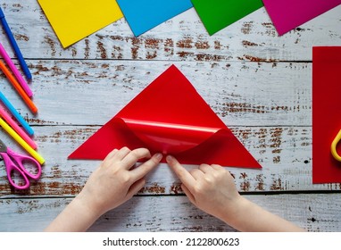 The Hands Of A Child Making Origami From Colored Red Paper