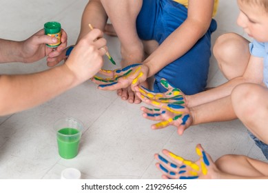 Hands Of A Child In Paint. Kids Hands Covered With Paint Top View.  Teacher Works With Children According To The Montessori Method And Paints Their Hands. 