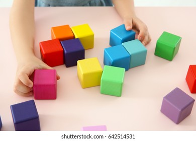 Hands of child playing with colorful cubes at home