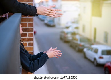 Hands Clapping On A Balcony Overlooking A Street With The Lights On