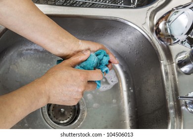 Hands Cleaning Dish Rag With Soapy Suds In Kitchen Sink