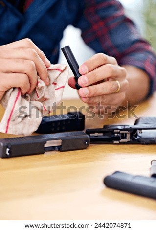 Hands, cleaning and man with firearm at table for safety, self defense and handgun assembly. Process, equipment and person with gun maintenance with cloth, magazine and wiping dust, dirt and oil