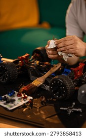 Hands cleaning small components of a disassembled remote control car. Maintaining hobby toys, hobbyist performing repairs