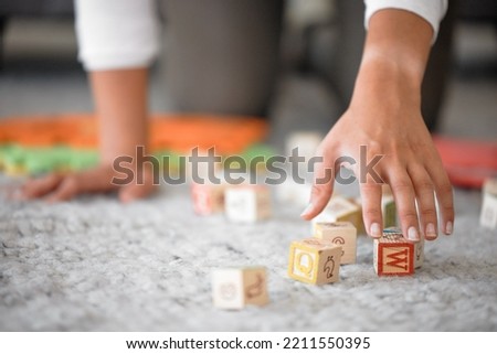 Hands, cleaning and toys with a woman or mother picking up building blocks in the house to clean or tidy. Hand, responsible and object with a female cleaner working on a home floor for housework