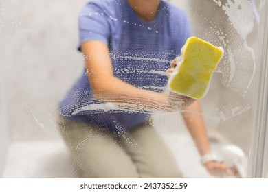 Hands are cleaning windows with sponge and detergent