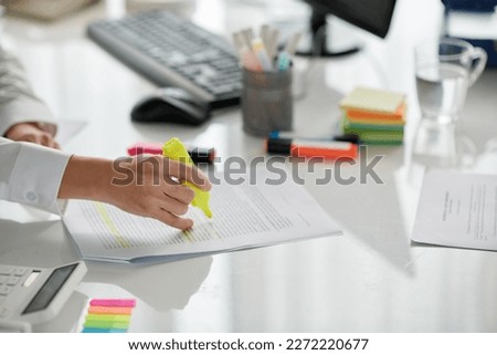 Hands of clerk highlighting part of document with yellow color