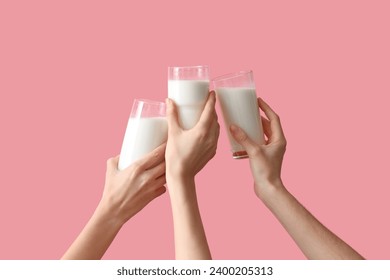 Hands clinking glasses of milk on pink background - Powered by Shutterstock