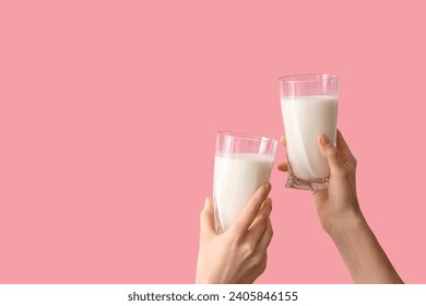 Hands clinking glasses of milk on pink background - Powered by Shutterstock