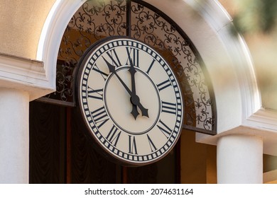 The hands of the clock 7 minutes to 12 on the large white dial of the outer clock on the yellow wall - Powered by Shutterstock