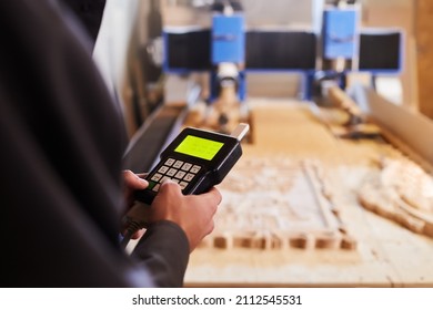 Hands Close Up Holding The Control Panel Of Wood Carving Machine. Modern Automatic Woodworking Machine With CNC. Furniture Production.