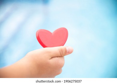 Hands Close Up Holding Red Heart With Blue Background