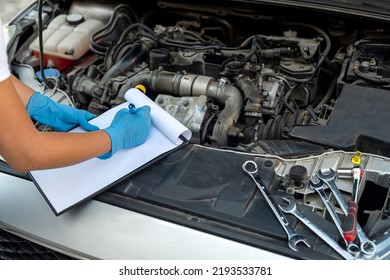 Hands Close Up Of A Smiling Young Female Mechanic Performing Diagnostics On A Car In An Auto Repair Shop. Woman Mechanic. Woman's Hands Under The Hood