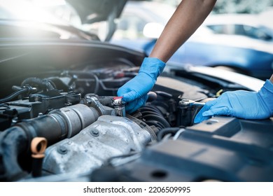 Hands Close Up Of A Smiling Young Female Mechanic Performing Diagnostics On A Car In An Auto Repair Shop. Woman Mechanic. Woman's Hands Under The Hood