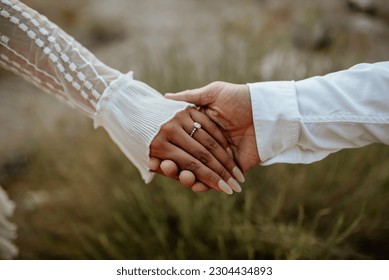 Hands close-up of boho couple in nature holding hands and walking, hugging having fun for their engagement photo session. - Shutterstock ID 2304434893