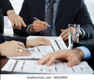 Hands in closeup at businessmeeting focusing on business documents and pointing at papers to sign.