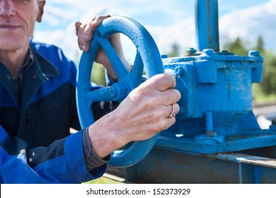 Hands close-up of senior manual worker turning cut-off valve at plant