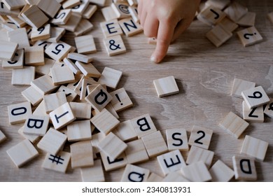 hands close-up, small child 3 years old plays wooden alphabet blocks, makes up words from letters, dyslexia awareness, learning difficulties, human brain development, happy childhood, selective focus