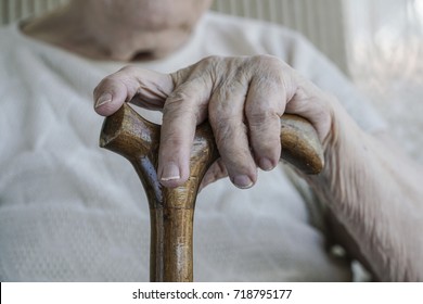 Hands, Closeup Wrinkled Hand Of A Senior Old Woman Or Man Holding A Wooden Walking Cane With Selective Focus. Wrinkled Body Parts Of Geriatric Old People Concept Photo. Holding Wooden Cane