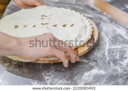 Hands closing the Ossetian pie stuffed with minced meat on the metal table of the restaurant kitchen. Stock photo © 