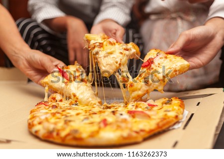 hands of colleague or friends eating pizza After a long meeting at office. They are having party at home, eating pizza and having fun. leisure, food and drinks, people and holidays concept 