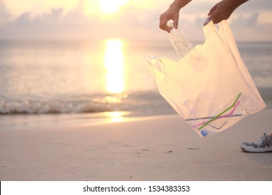 Hands Collecting Plastic In A White Plastic Bag On The Beach.Pollute The Ocean.Help To Keep Nature Clean, Garbage From The Beach.Ecological Problems.Environmental Crisis.Coastal Cleanup Day Concepts